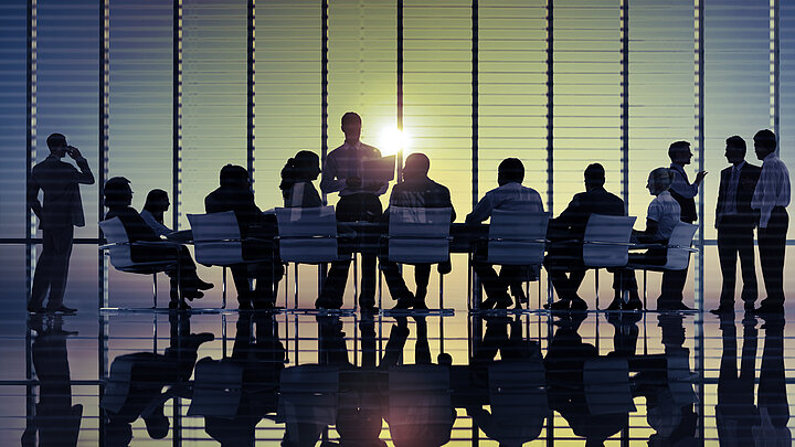 Zdjęcie grupy ludzi podczas spotkania managerskiego na tle okien.